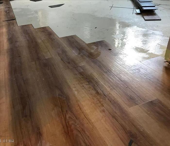 Partially removed laminate flooring showing water underneath it