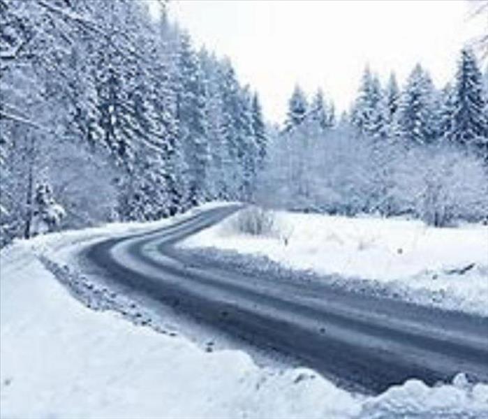 An image of a snowy road and snowcovered trees