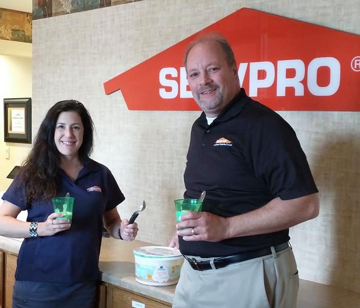 A dark haired woman wearing a blue SERVPRO polo and a tall man wearing a black SERVPRO polo
