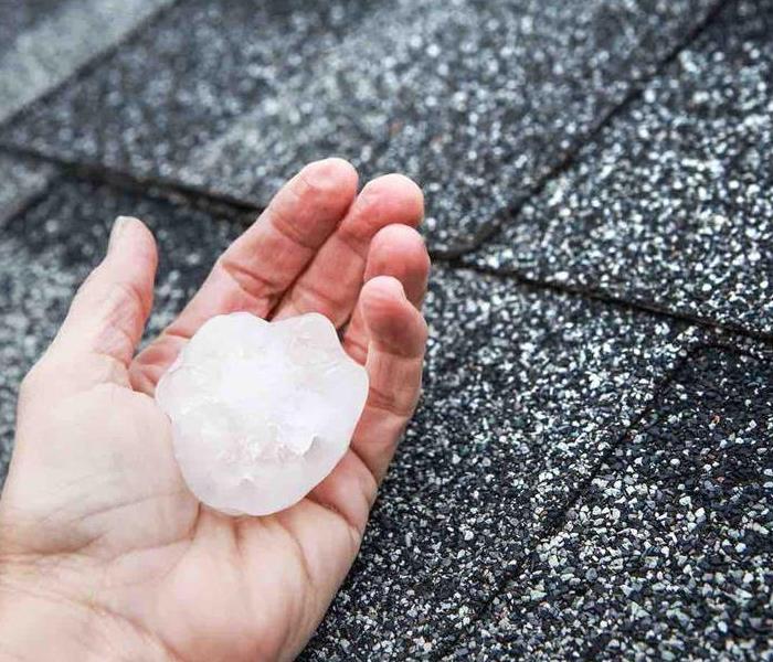 a Caucasian hand holding a hail ball outside