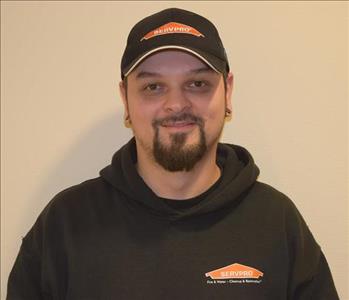 A man wearing a black SERVPRO hat and hoodie.
