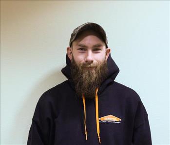 A bearded man wearing a black SERVPRO hoodie and baseball hat.