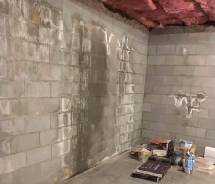 Basement brick wall with water damage and white crystals growing on it